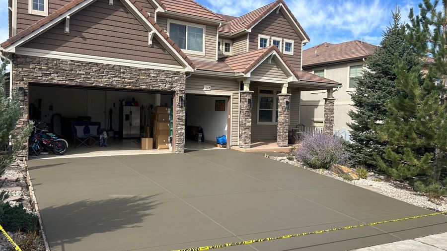 Front driveway of a brick house with a three-car garage, concrete apron, and yellow caution tape across the front