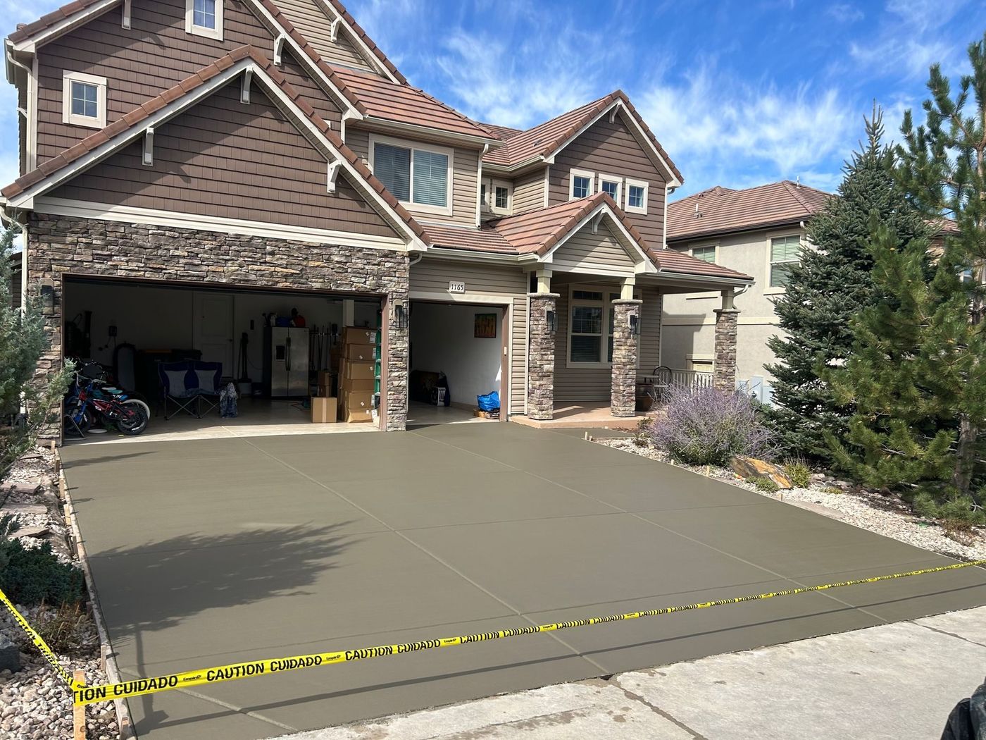 Front driveway of a brick house with a three-car garage, concrete apron, and yellow caution tape across the front