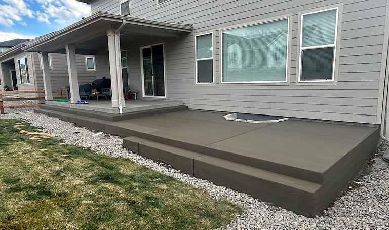 Back patio with gray siding, white trim, and a large dark gray concrete step platform