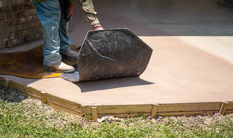 Worker lifting rolled carpet on a concrete slab outdoors