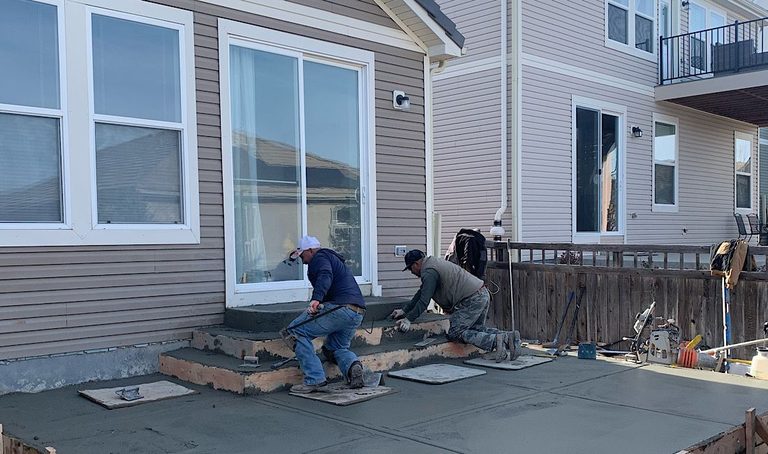 Crew forming and pouring concrete steps at the back door of a two-story home